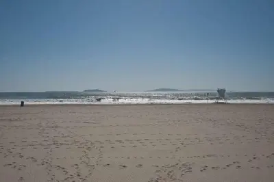a beach with footprints in the sand and the ocean at Beautiful Ocean Front Coastal Sunset Beach House in Oxnard