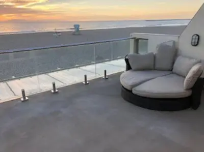 a white couch sitting on a balcony with the beach at Beautiful Ocean Front Coastal Sunset Beach House in Oxnard