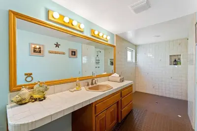 a bathroom with a sink and a large mirror at Beautiful Ocean Front Coastal Sunset Beach House in Oxnard