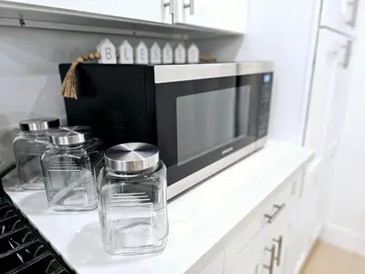 a kitchen counter with three glass jars and a microwave at The Heart Of LA House in Los Angeles