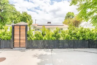 a fence with a wooden door in front of a house at New luxury entertaining house with Pool Spa Sauna Tesla charger Pets in Los Angeles