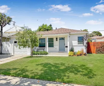 a white house with a fence in a yard at El Nido Beachlife Cottage in South Bay Los Angeles in Redondo Beach