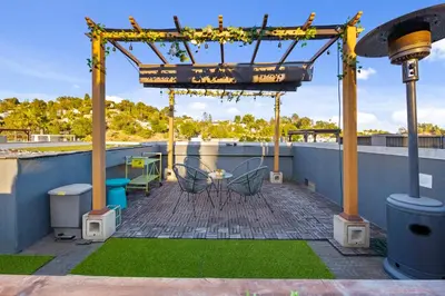 a patio with a table and chairs on a roof at Chic Silver Lake Oasis with Breathtaking City Skyline Views, Private Rooftop & Garage in Los Angeles
