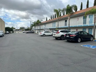 a parking lot with cars parked in front of a building at Villa Inn Anaheim in Anaheim