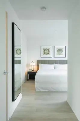 a bedroom with a white bed and a mirror at Level Long Beach - East Village in Long Beach
