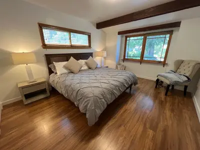 a bedroom with a bed and a chair and two windows at Villa La Reforma - Newly Designed 4BR HOUSE & POOL in Los Angeles by Topanga in Los Angeles