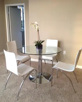 a glass table with white chairs and a vase with flowers on it at Awesome Top Floor 2-Bedroom with Balcony in Los Angeles