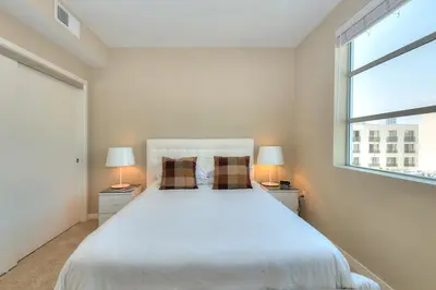 a bedroom with a large white bed with two lamps at Awesome Top Floor 2-Bedroom with Balcony in Los Angeles