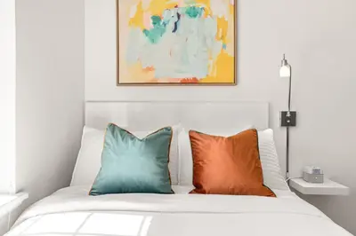 a bed with two pillows and a painting above it at The Varden - A Self-Service Micro Hotel in Long Beach