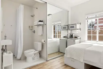 a white bathroom with a bed and a toilet at The Varden - A Self-Service Micro Hotel in Long Beach