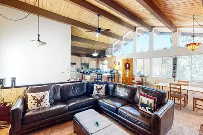 a living room with a leather couch and a table at Edelwiess Wonder in Crestline