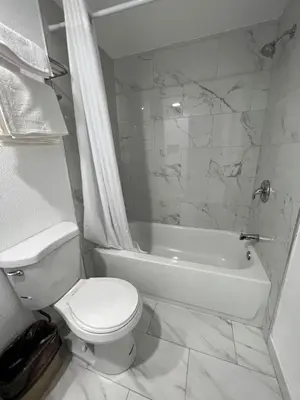 a white bathroom with a toilet and a bath tub at Goldstar Inn in Los Angeles