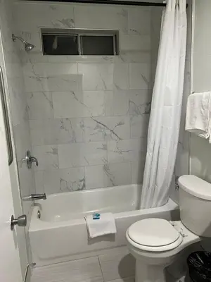 a white bathroom with a toilet and a tub and a toilet at Goldstar Inn in Los Angeles