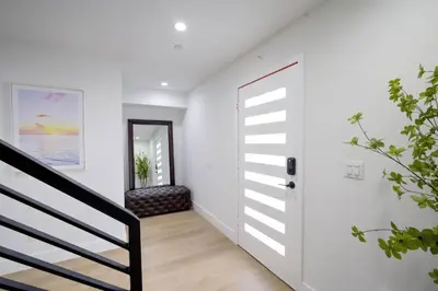 a white hallway with a staircase and a door at Modern Apartment in Studio City in Los Angeles