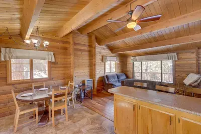 a dining room and living room of a log cabin at Pine Mountain Club Cabin Rental with Pool Access! in Pine Mountain Club