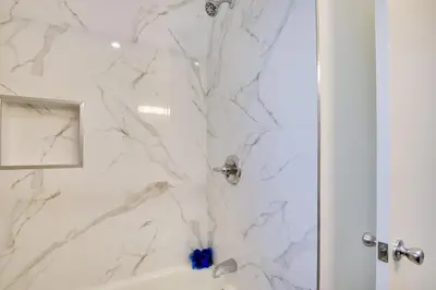 a bathroom with a shower with white marble walls at Home Between Los Angeles and Disney! Patio, Yard in Pico Rivera