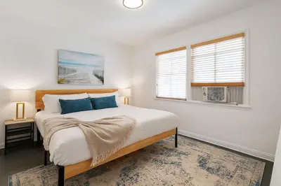 a white bedroom with a bed and two windows at Quaint 1BD 1BA Bungalow in Los Angeles