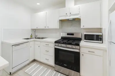a white kitchen with a stove and a microwave at Quaint 1BD 1BA Bungalow in Los Angeles