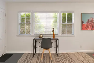 a table and a chair in a room with windows at Quaint 1BD 1BA Bungalow in Los Angeles
