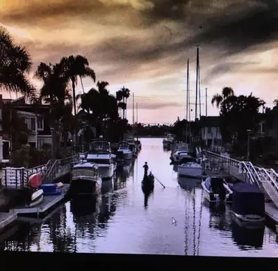 a person is walking through a river with boats at The Heart of Belmont Shore in Long Beach