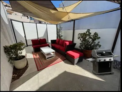 a patio with two red chairs and a grill at The Heart of Belmont Shore in Long Beach