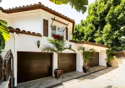 a white house with two garage doors and palm trees at Bel Air Luxury Villa 6 bedrooms entire house Los Angeles in Los Angeles