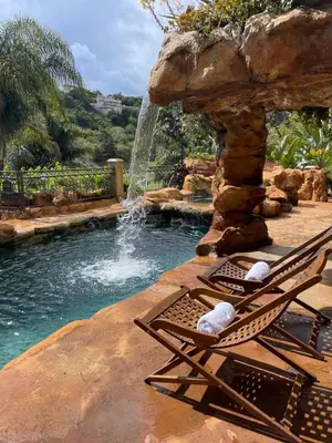 a pool with a chair next to a waterfall at Bel Air Luxury Villa 6 bedrooms entire house Los Angeles in Los Angeles