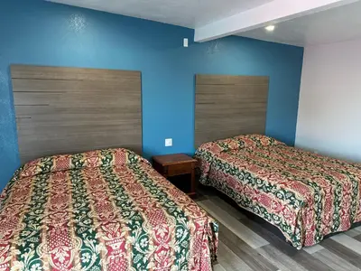two beds in a room with blue walls at Rancho Motel - Ontario Airport in Ontario