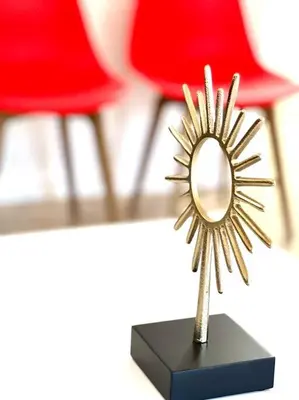 a gold starburst mirror on a black stand with a red chair at Cozy house near Disney, Knott’s & Beach!! in Fullerton