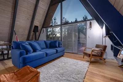 a blue couch in a living room with a large window at Hot Tub-EV-Kid Friendly-Arcade Game-BBQ-Fire Pit in Lake Arrowhead