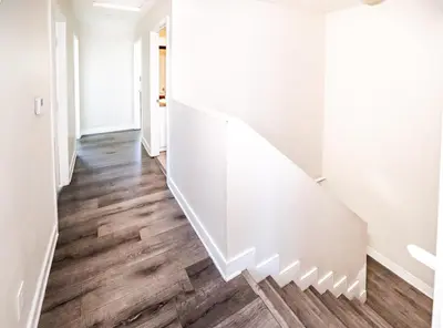 a white staircase in a hallway with wood floors at Large Condo Sleeps 10 near Downtown Los Angeles in Los Angeles