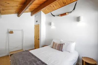 a bedroom with a white bed and a wooden ceiling at Le Chalet of Arrowbear Lake in Running Springs