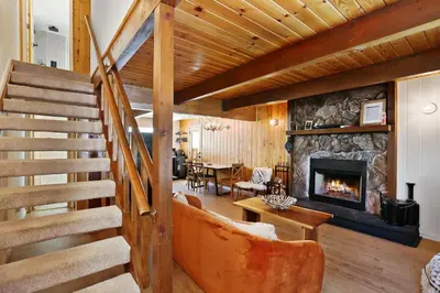 a living room with a staircase and a fireplace at Le Chalet of Arrowbear Lake in Running Springs