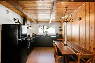 a kitchen with a wooden table and a black refrigerator at Le Chalet of Arrowbear Lake in Running Springs
